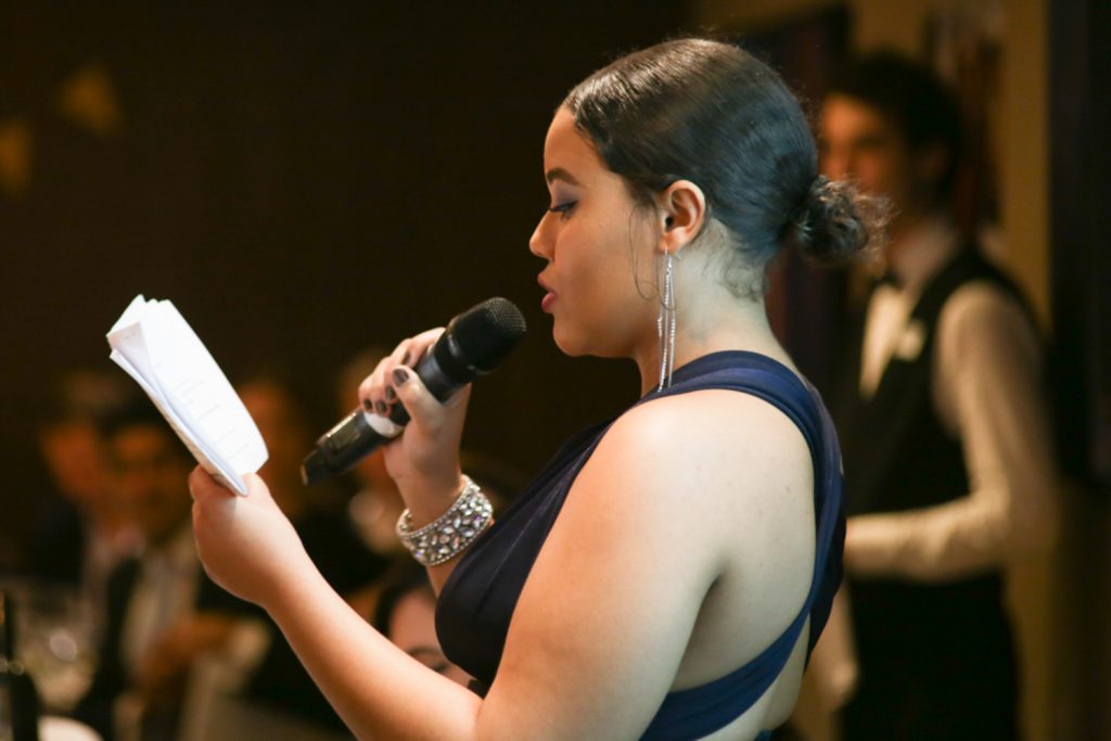 Woman in navy dress making a speech at a corporate event