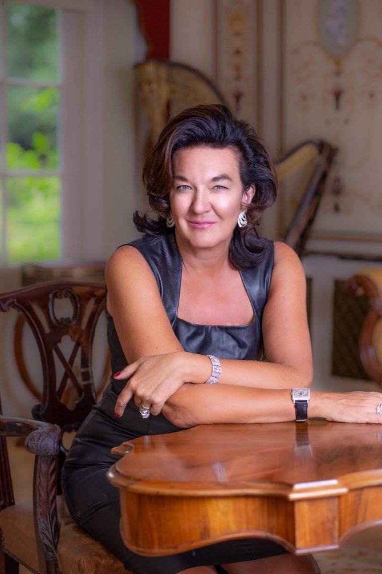 Smart woman in black leather dress sitting at mahogany table